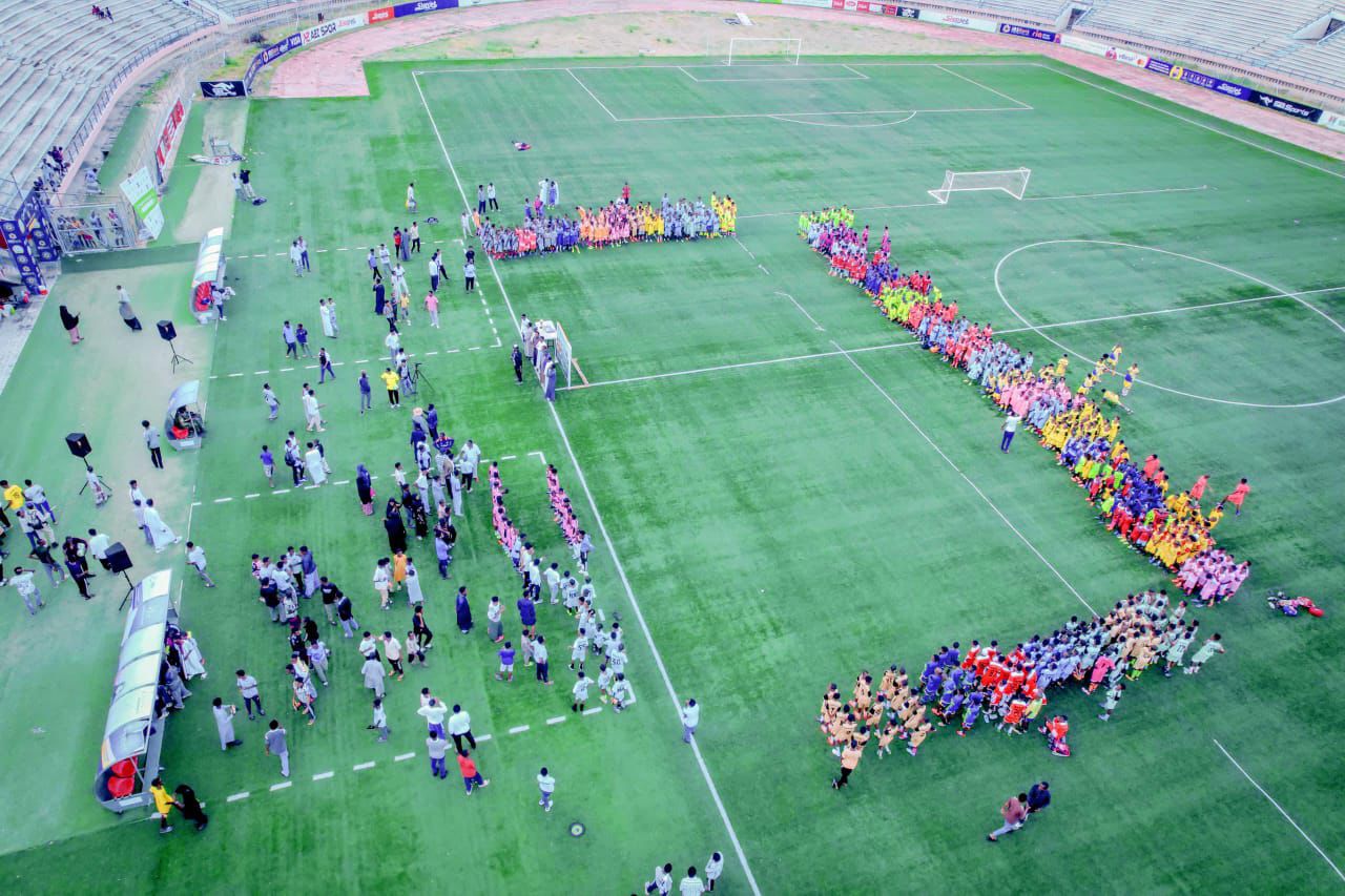 Mentor sharing tactics with neighbourhood kids around a football