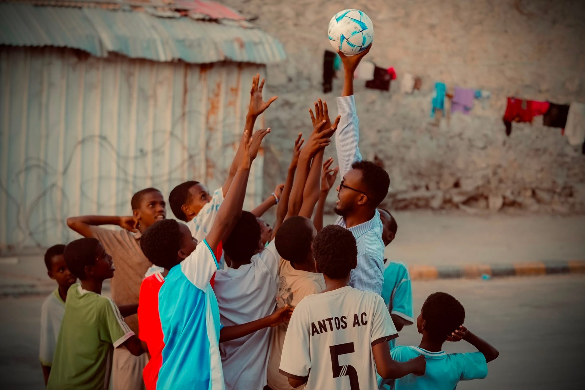 Higsi Foundation coach with children reaching for a football
